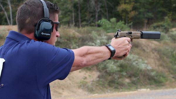 Man Shooting a Pistol with a Sound Suppressor Attached on an Outdoor Range